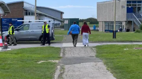Student and parent walking along a path into a school with the building in the background.
