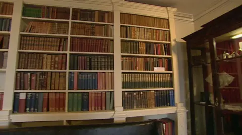 The library with hundreds of old-looking books in a white bookcase.
