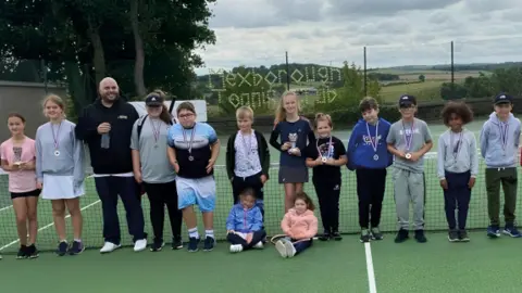 CISWO Young members of Mexborough Tennis Club pose for a photograph on a tennis court with an adult