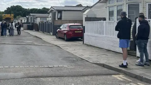 A general view of the Traveller site, where people are seen people are walking around in front of mobile homes.