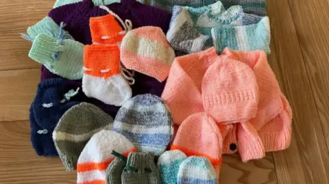 A picture of a number of knitted items. There are different colours, shapes and patterns.