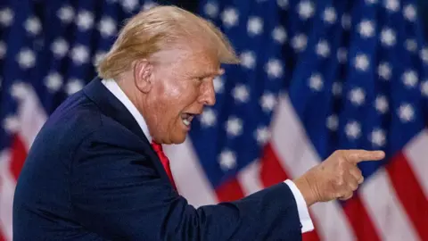 Reuters Donald Trump points a finger while standing in front of a US flag during a rally in St Cloud, Minnesota, on 27 July