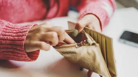A woman sitting at a table reaching into a purse.