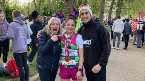 Ashley Delgado Ashley Delgado celebrates with her family after finishing the London Marathon as her mum points at her with her mouth open in excitement while her brother smiles at the camera