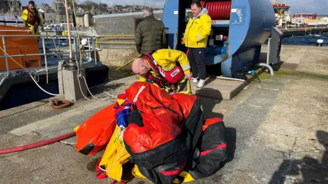 Lifeboat crew member gathering life raft