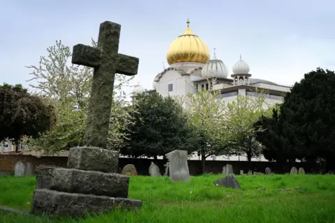 Getty Images The golden dome of the Sri Guru Singh Sabha Sikh temple in Southall rises up behind the graves of Havelock cemetery