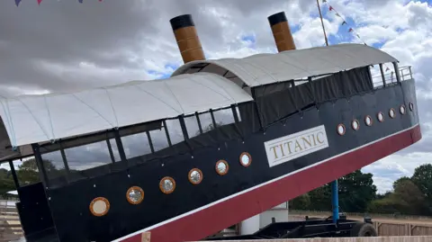 BBC An outdoor hydraulic slide designed to look like Titanic. It has a red and blue exterior with a large sign that reads "Titanic". 
