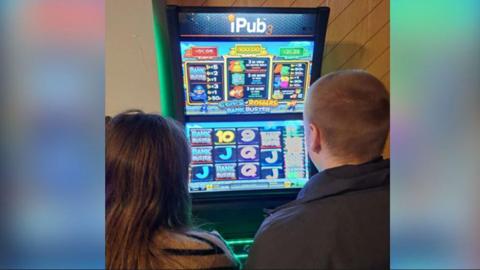 Two people play on an ipub fruit machine 
