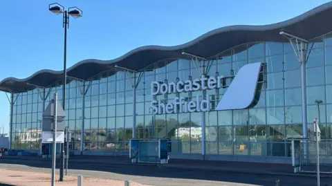 LDRS Exterior shot of Doncaster Sheffield Airport on a sunny day, showing glass frontage reflecting other buildings