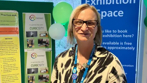 Physiotherapist Phillipa Newton-Cross standing in front of some information signs