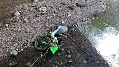 Brent Council A Lime bike lying on its side in a stream of water in Brent