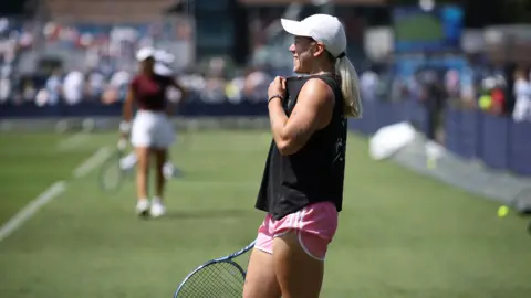 Getty Images Sonay Kartal of Great Britain has a hit on the practice court during the Lexus Eastbourne Open at Devonshire Park on June 21, 2025 in Eastbourne, England. She wears a black top, pink shorts and a white baseball cap.