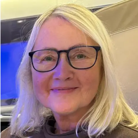 Angela Jenkins Angela Jenkins has shoulder length blonde hair and is wearing glasses.