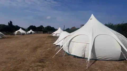 Picture of white yurts in a field.