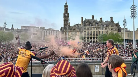 People singing in front of crowd with flares