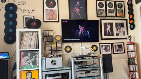 A wall filled with Elvis records, tapes, and photos