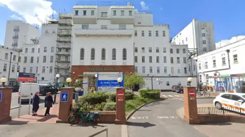 A general view of the exterior of St Helier Hospital shows white building with red brick entrance and wall