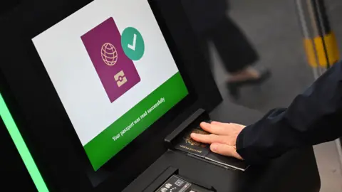 Close up of a person's hand wearing a wedding ring holding down a British passport on a scanner during a demonstration of the new system in September at the Eurostar terminal in Folkestone.