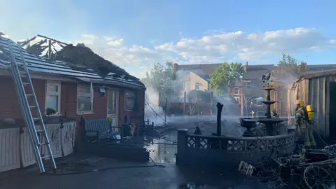 Derbyshire Fire & Rescue Service An image showing the damaged caused by a fire which damaged a bungalow and garages including a hole in the bungalow's roof.