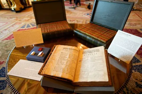 PA Media Two cases which lay open on a table contain volumes of books while on book is left opened with the title "The Tempest" clearly seen on one page.