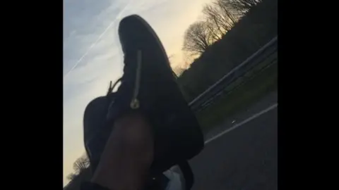 Feet out of car window on motorway - no socks on 