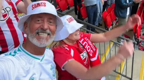 John Sorrell John Sorrell with his wife in the stands watching Southampton. They are both wearing team shirts and celebrating.