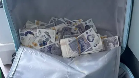 West Yorkshire Police A suitcase full of counterfeit £20 bank notes.