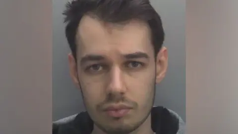Mugshot of Tyler Webb with short hair looking directly at the camera against a grey background.