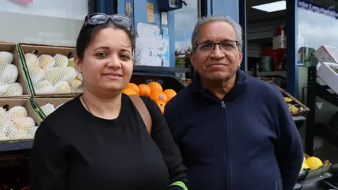 Saurabhi Bhave and her dad Mukund Vaidya standing in front of a fresh fruit and vegetable display outside a shop in Leicester
