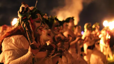 CHARLOTTE ML A row of women in white dresses and face paint