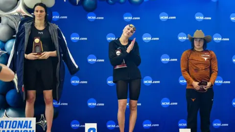 Getty Images Lia Thomas (left) accepts the winning trophy at the NCAA championships in 2022