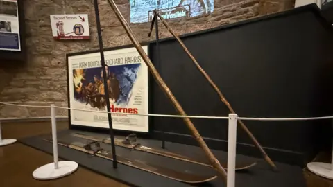 A set of wooden skiis in front of a vintage movie poster