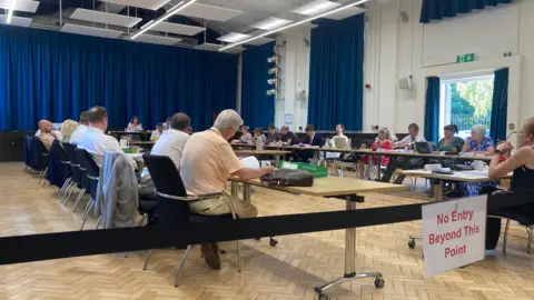 A shot showing the council chamber during the annual general meeting - showing councillors sat across several rows of chairs.