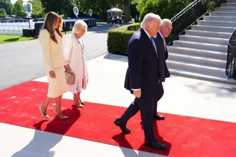 PA Queen Camilla and Melania Trump, both in light-coloured dresses, follow Donald Trump and King Charles, both in dark suits, down a red carpet