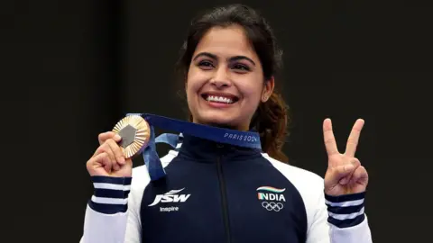 Getty Images Bronze medalist Manu Bhaker of Team India poses on the podium holding her medal during the Women's 10m Air Pistol Final medal ceremony on day two of the Olympic Games Paris 2024 