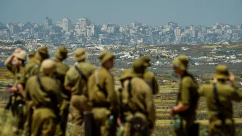 Israeli soldiers looking at the destroyed Jabalia area, in the northern Gaza Strip, from near Kibbutz Nir Am, Israel (22 April 2026)