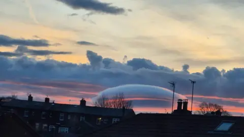 David Fletcher A cloud that resembles a flying saucer can be seen in an orange sky above houses