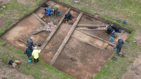 An aerial view of an Anglo Saxon building with volunteers working 