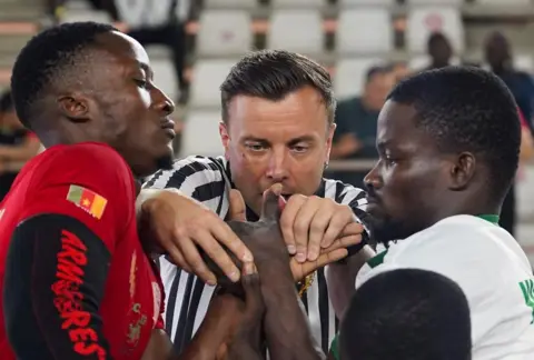 MARVELLOUS DUROWAIYE / REUTERS A referee checks the positions of the hands of two armwrestlers. 
