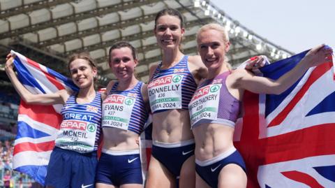 Lauren McNeil, Clara Evans, Abbie Donnelly and Calli Hauger-Thackery pose with a British flag after winning team gold in the women's half marathon event at the 2024 European Athletics Championships