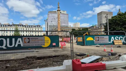 Fencing, signs and cones around the entrance to George Square, with most of the ground having been dug up