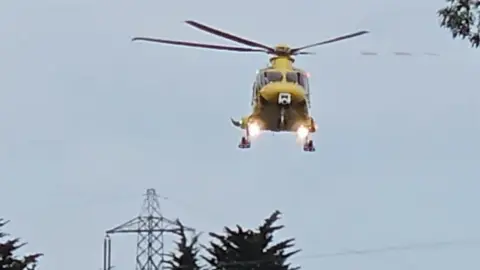Barry Martin A helicopter hovering over the A30 in daylight.