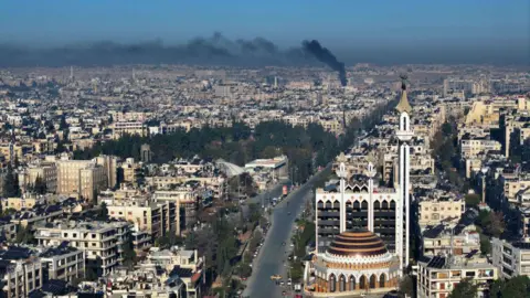 Getty Images Gambar udara Aleppo dengan asap hitam membubung di atas kota. 