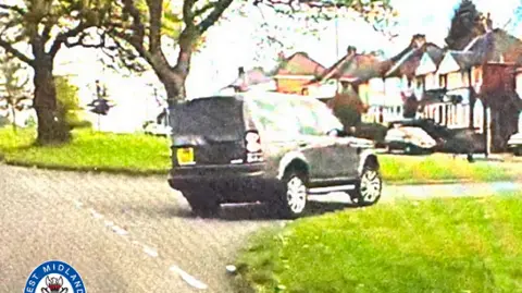 West Midlands Police A grainy image of a black Land Rover driving across an intersection