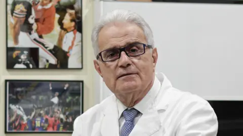 Dr Ramon Cugat in his office, next to a photograph of Pep Guardiola.