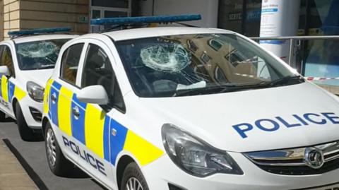 Two police cars with smashed windscreens