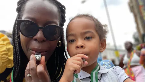 Family handout / PA Sheyi and her daughter Isabella blowing their whistles at a previous Notting Hill Carnival