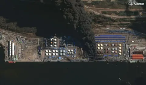 Vantor An enormous black smoke cloud coming from a Russian oil storage facility next to the water