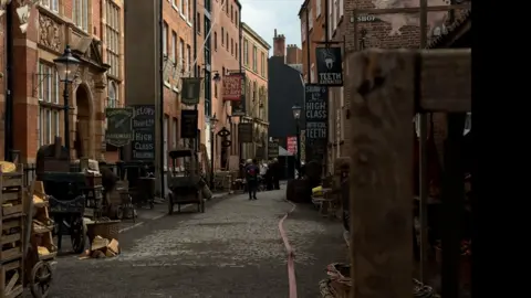 A cobbled street is dressed as Victorian London, with period signs, props, and buildings.
