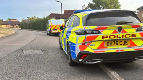 Police vehicles are parked on the road.